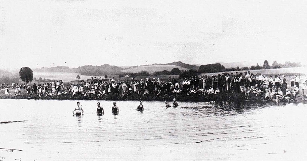 Wettschwimmen im “Strandbad Wahlscheid” in den 1930er Jahren. Am Aggerufer haben sich zahlreiche Zuschauer eingefunden. darunter Parteigrößen und Ortspolizist Grammich.
