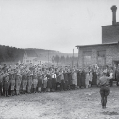 Bannerhissen 1936 auf dem Fabrikgelände der Firma Fischer in der Hermann-Löns-Straße. Links neben der Tür der Fabrikant Johann Fischer(mit Hut) und rechts daneben seine
Ehefrau Mechtilde. Das helle Haus im Hintergrund ist das Haus Höndgesberg auf der Kieselhöhe.