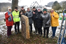 (von links) Doro und Paul Hoeher, Klaus und Cäcilia Obermierbach, Steinmetz Markus Weisheit, Michaela Röhrig, Gitti Bäcker-Gerdes und Ulrike Clever freuen sich über das sichtbare Zeichen ihres Sieges am Eingang von Neuhonrath. Foto Heinz Lenz