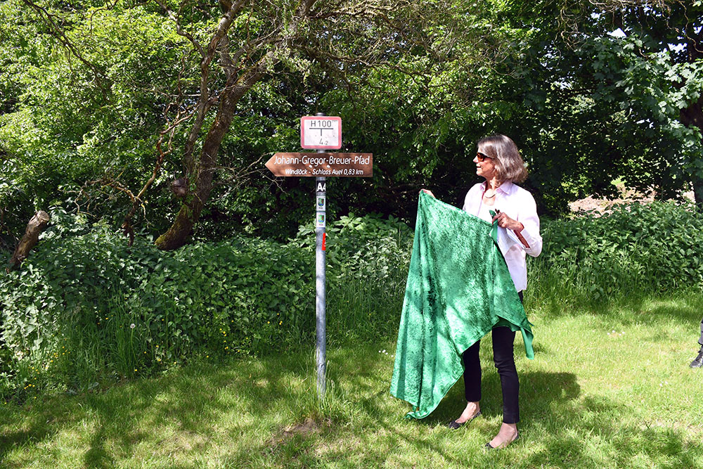 Tatjana von la Valette enthüllte das neue Wanderpfad-Hinweisschild. Der Verkehrs- und Verschönerungsverein Wahlscheid/Aggertal e.V. hatte den beliebten Wanderweg zwischen Schloss Auel und Windlöck  mit neuen Hinweisschildern versehen, die ihn jetzt als „Johann-Gregor-Breuer-Pfad“ ausweisen. Mit großer Sicherheit haben Adam Joseph und Johann Gregor Breuer diesen Weg oft beschritten. 